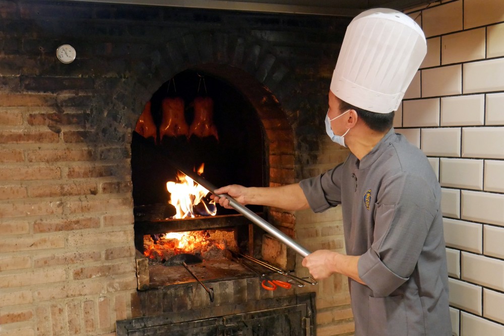 Chef horneando pato laqueado en el restaurante HUTONG. 